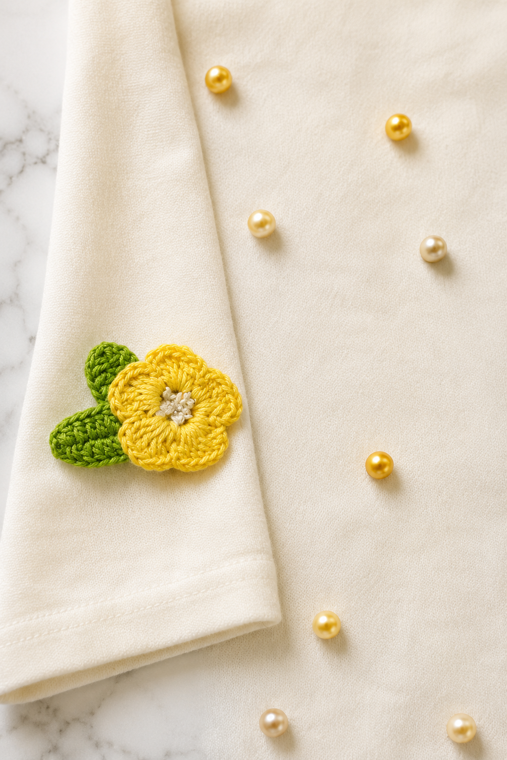 Close-up of the Lemon Petal Pearl Women's T-Shirt highlighting the yellow crochet blooms and ombré pearls on French Terry fabric.