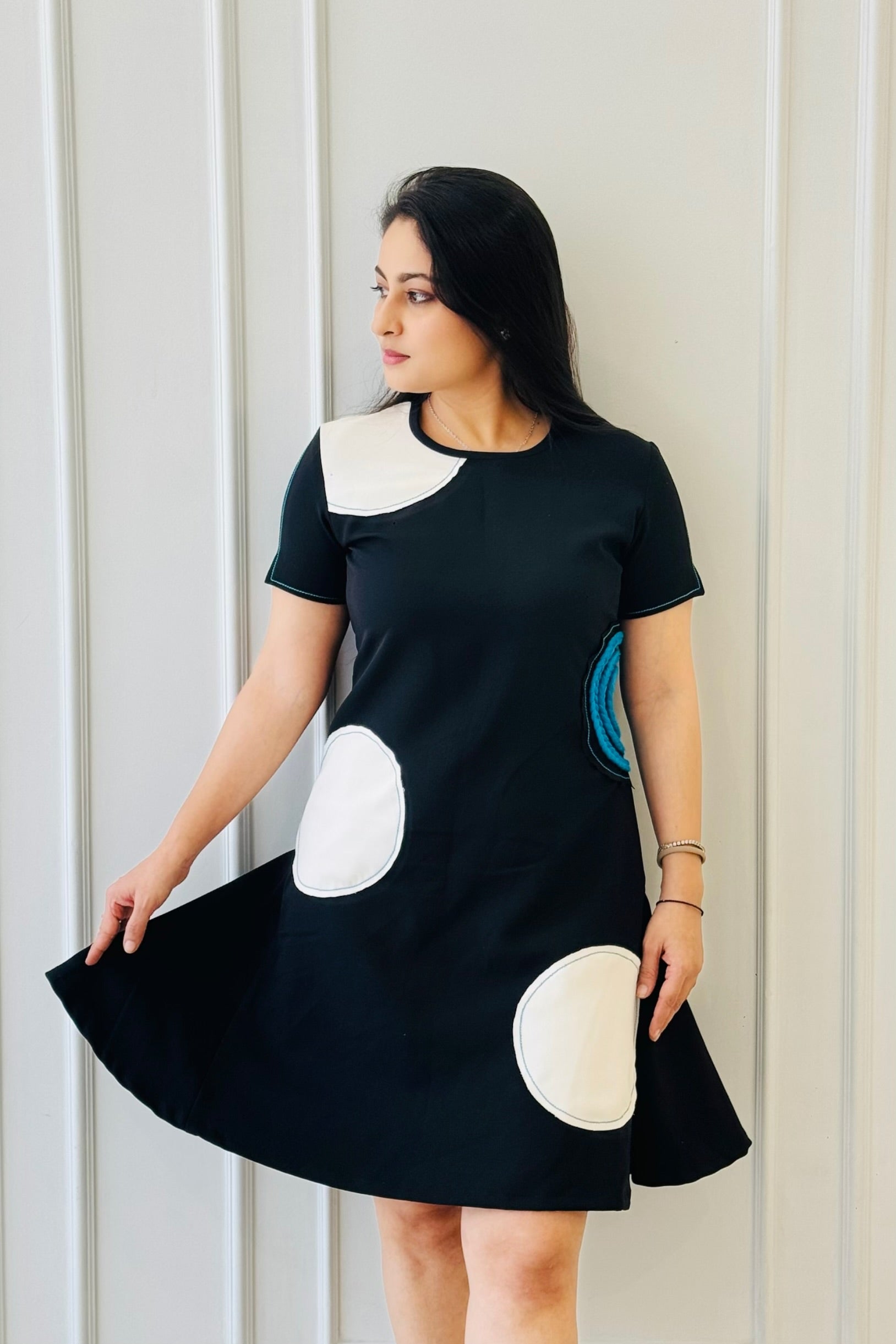The Dot Women's Dress in black featuring oversized polka-inspired appliqué detailing with a blue braided accent.
